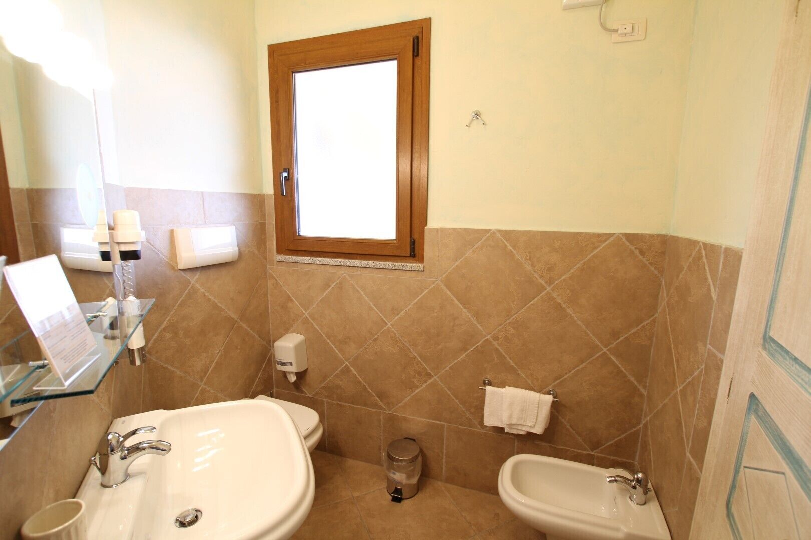 A bathroom with two sinks, a mirror, a window, and a towel rack.