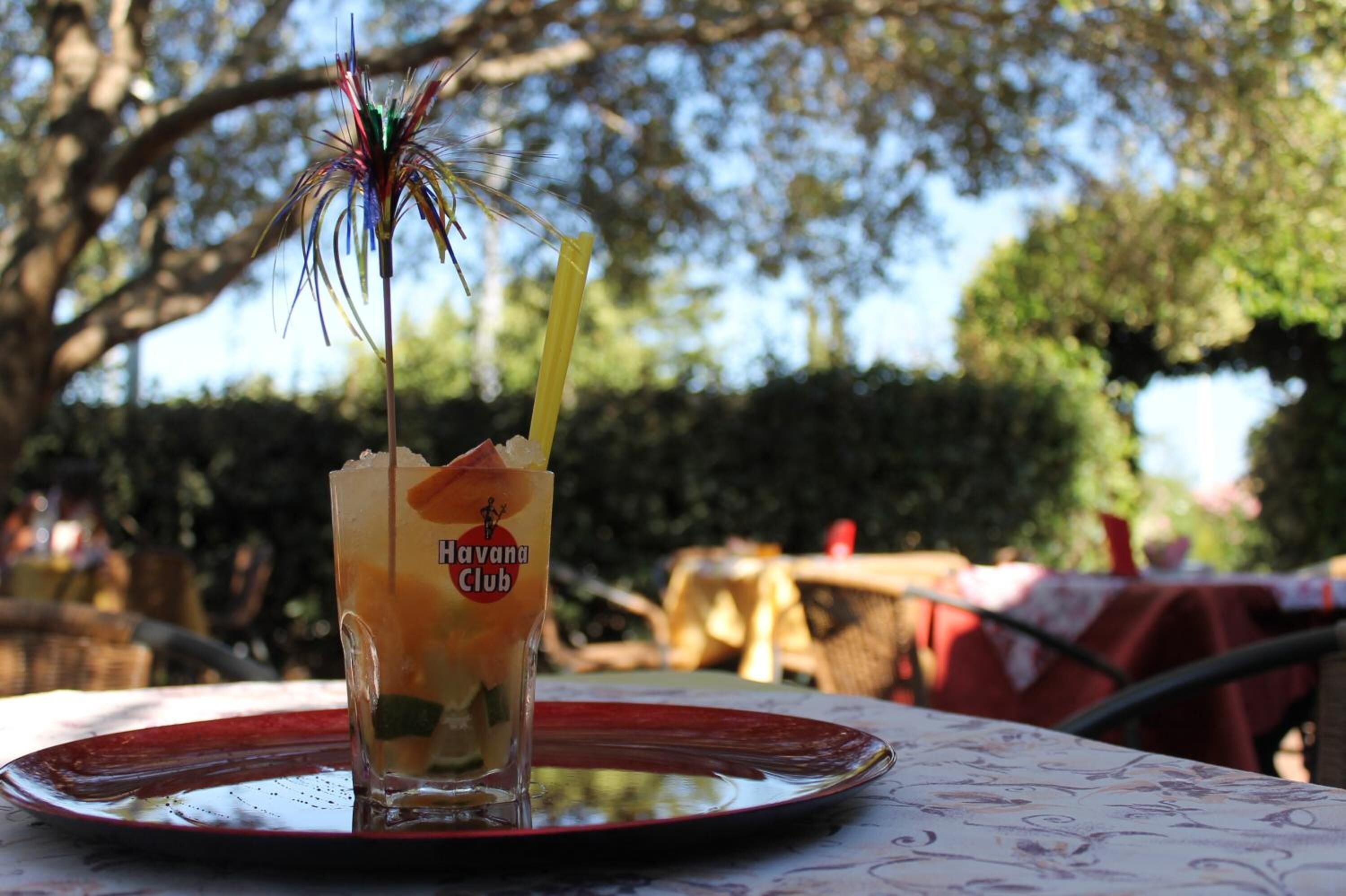A glass of drink with a straw and a decorative item on a table outdoors.