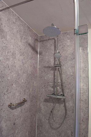 A shower with a handheld showerhead and a handheld shower bar.
