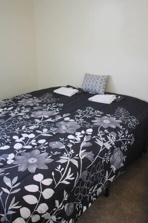 A bed with a black and white floral bedspread, two pillows, and a small bedside table. - 1 bedroom apartment within sight of Fort Sill (Lawton)
