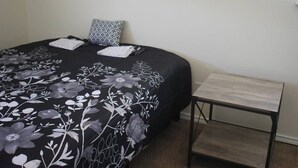 A bed with a floral bedspread, a patterned pillow, and a small wooden nightstand. - 1 bedroom apartment within sight of Fort Sill (Lawton)