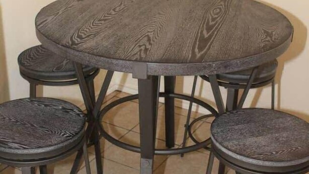 A round dining table with four stools, all featuring a dark, textured surface and metal legs. - 1 bedroom apartment within sight of Fort Sill (Lawton)
