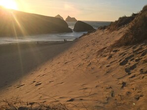 A sandy beach with large rocks in the background and a clear sky. - Luxury Holywell Beach House with Hot Tub (Holywell)