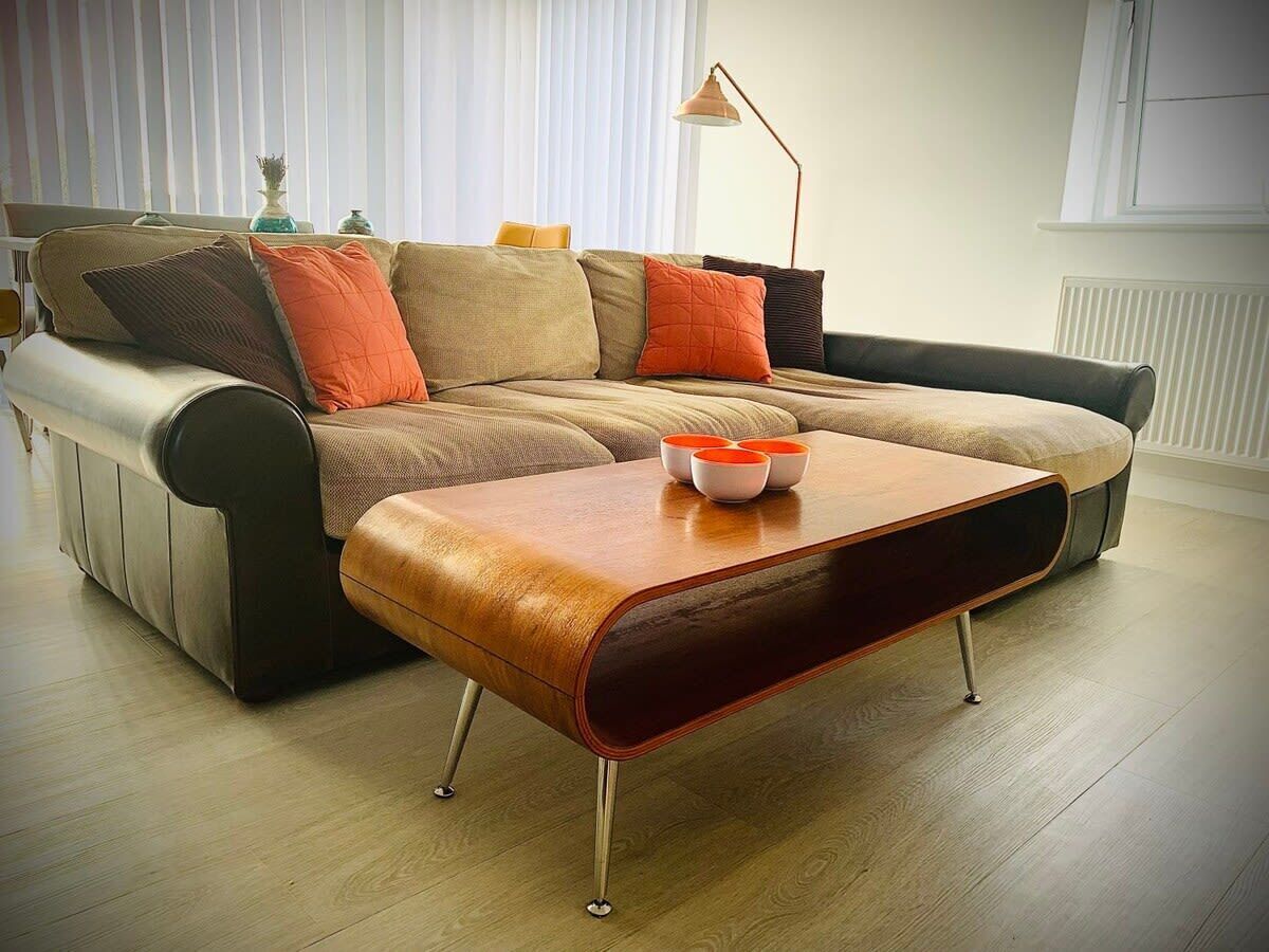 Ein modernes Wohnzimmer mit Ledersofa, Couchtisch aus Holz und Stehlampe.