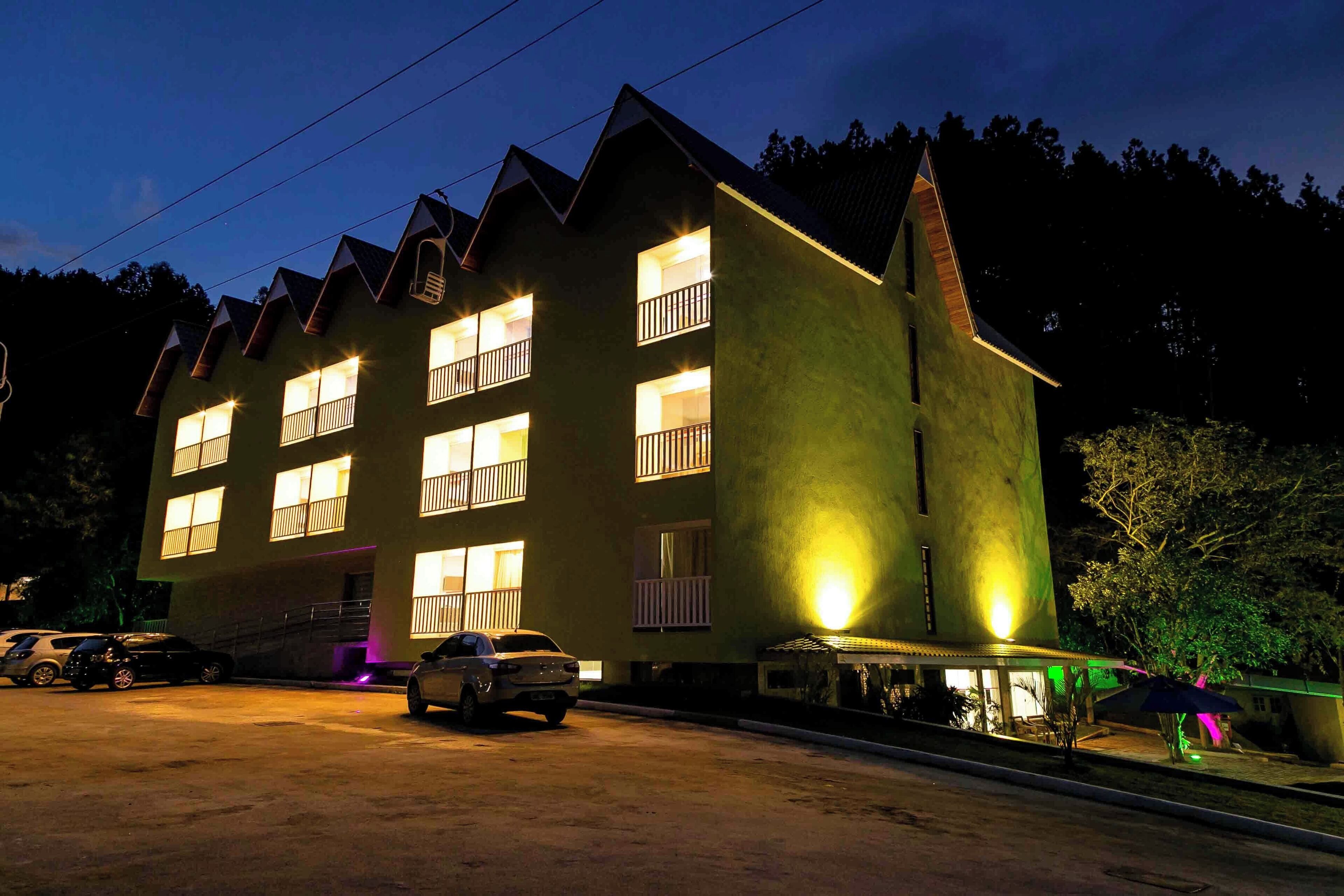 A multi-story building with balconies and a parking area.