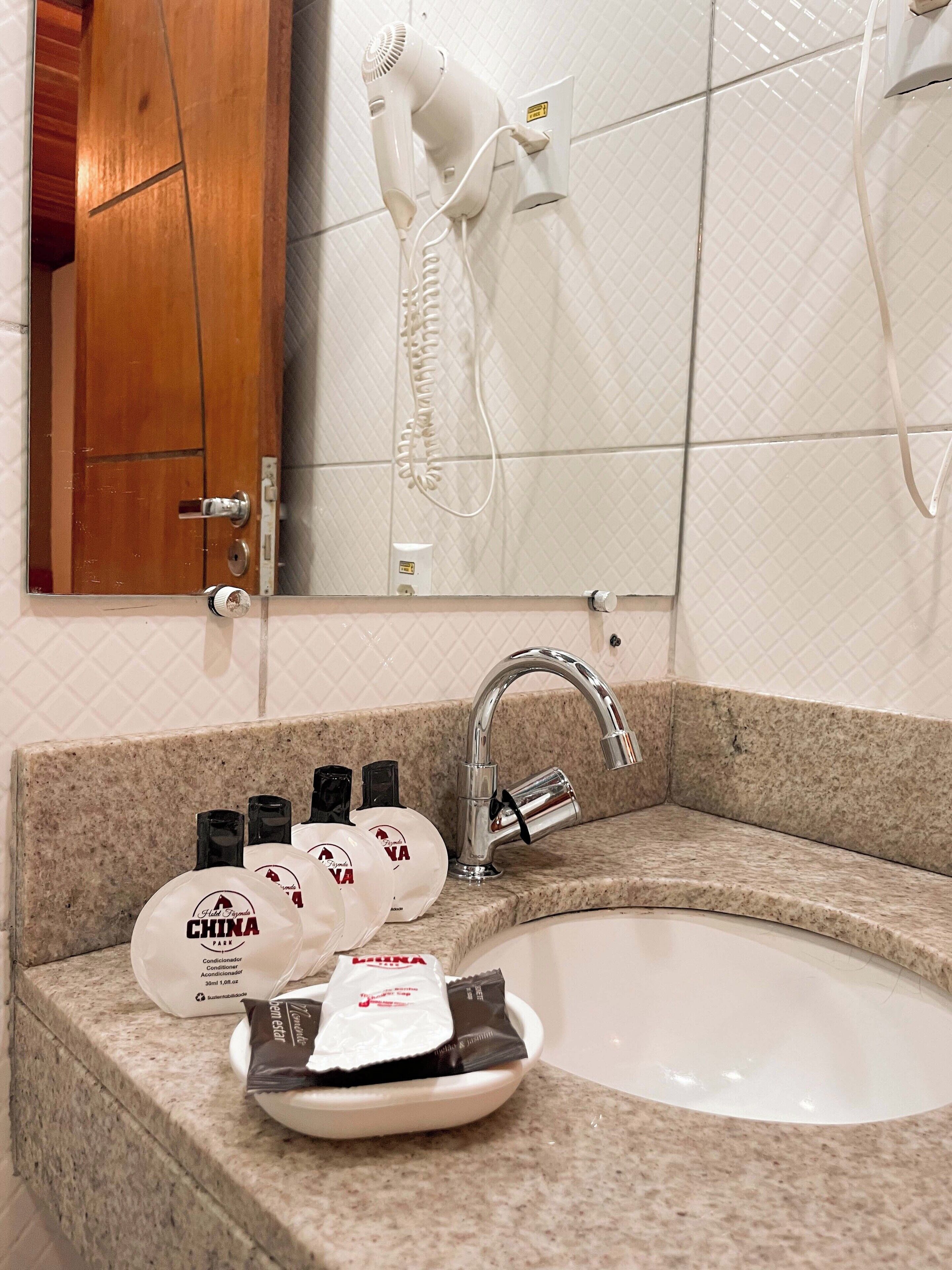 Un baño con lavamanos, secador de pelo y artículos de aseo.