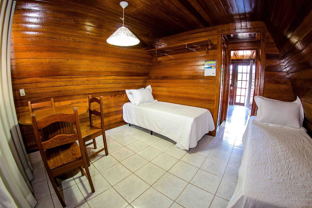 Een kamer in chaletstijl met houten wanden, een bed, een stoel en een kleine tafel.