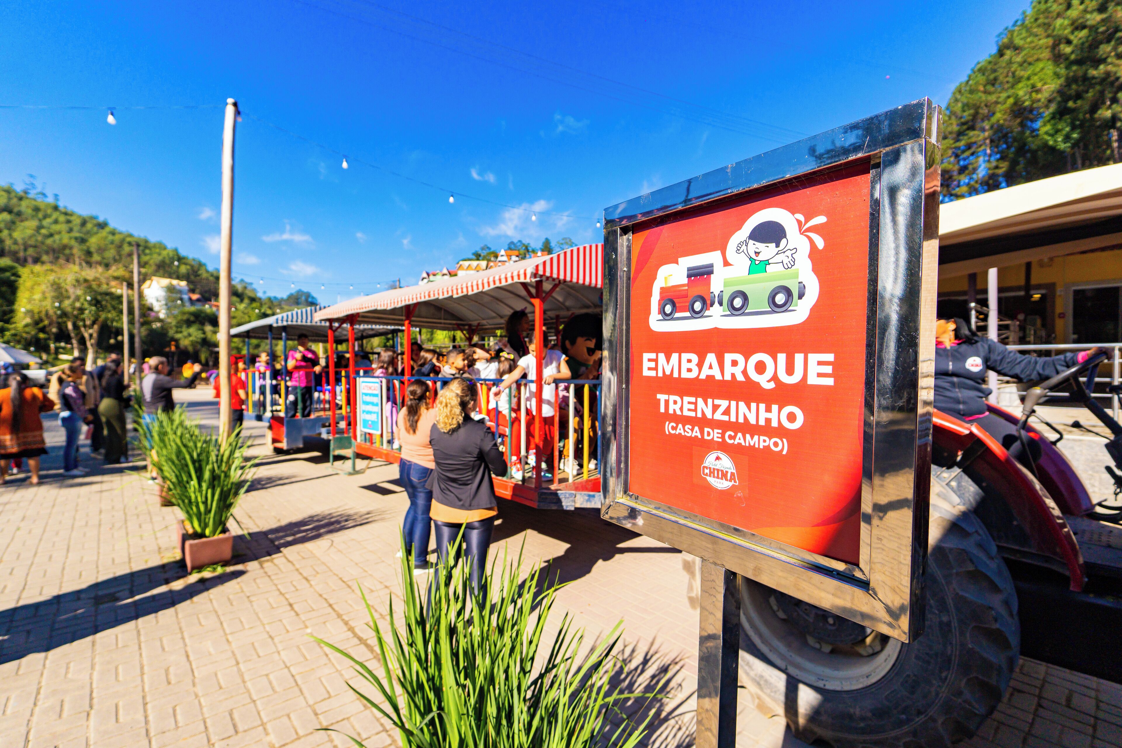 A sign for 'EMBARQUE TRENZINHO' with a logo of a train and a child.