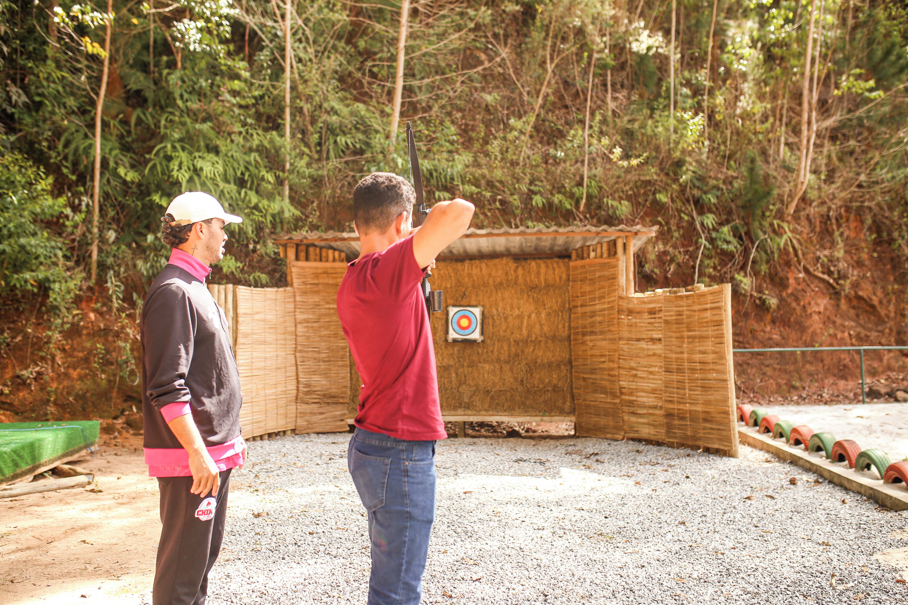 A man aiming at an archery target in a forested area.