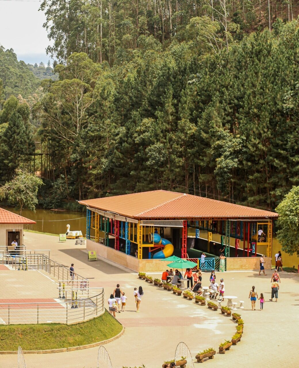 Un espacio al aire libre cubierto con un parque infantil, asientos y un pequeño edificio.