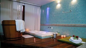 A spa room with a wooden tub, a massage table, and a blue-tiled wall. - China Park Eco Resort (Domingos Martins)