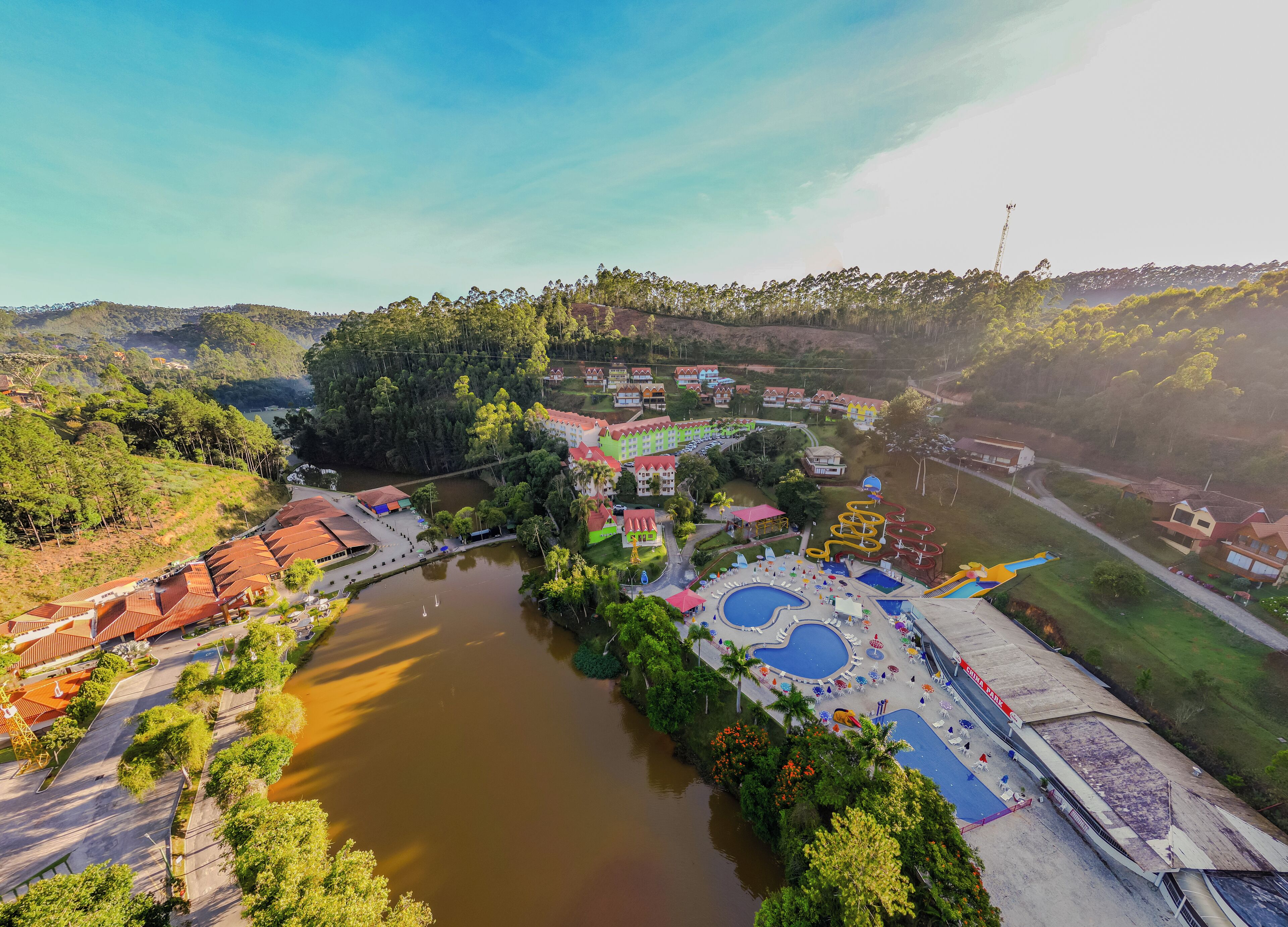 An aerial view of a resort with a large pool, water slides, and a river.