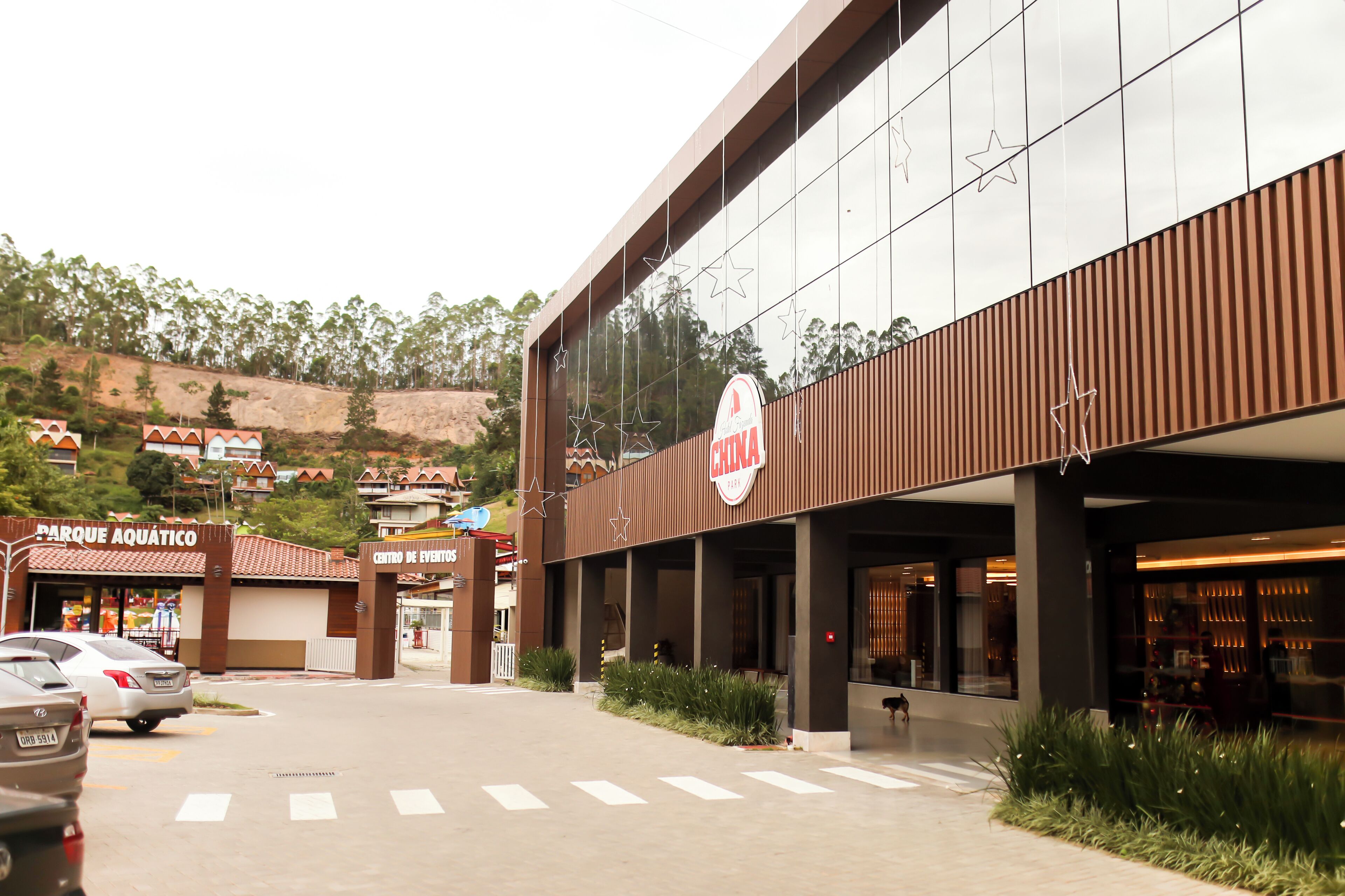 A modern building with a sign for 'China Park' and a 'Centro de Eventos' sign. There are cars parked in front, and a pedestrian crossing is visible.