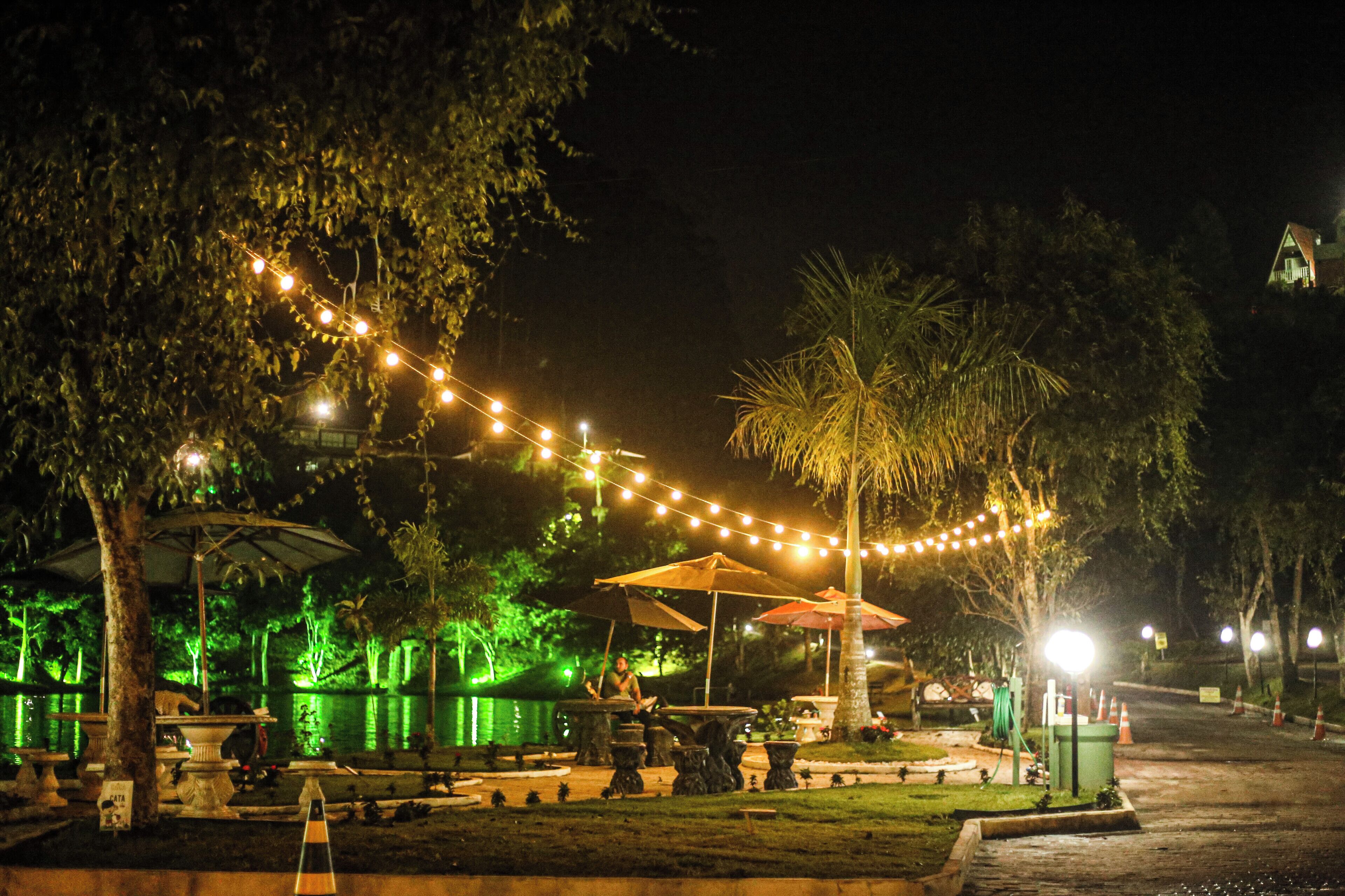 An outdoor area with string lights, umbrellas, and a fountain.
