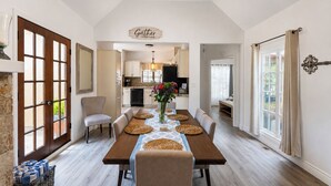 A dining area with a long table, chairs, and a central vase with flowers. - Large deck, open floor plan, walk to shopping. (Carmel By the Sea)