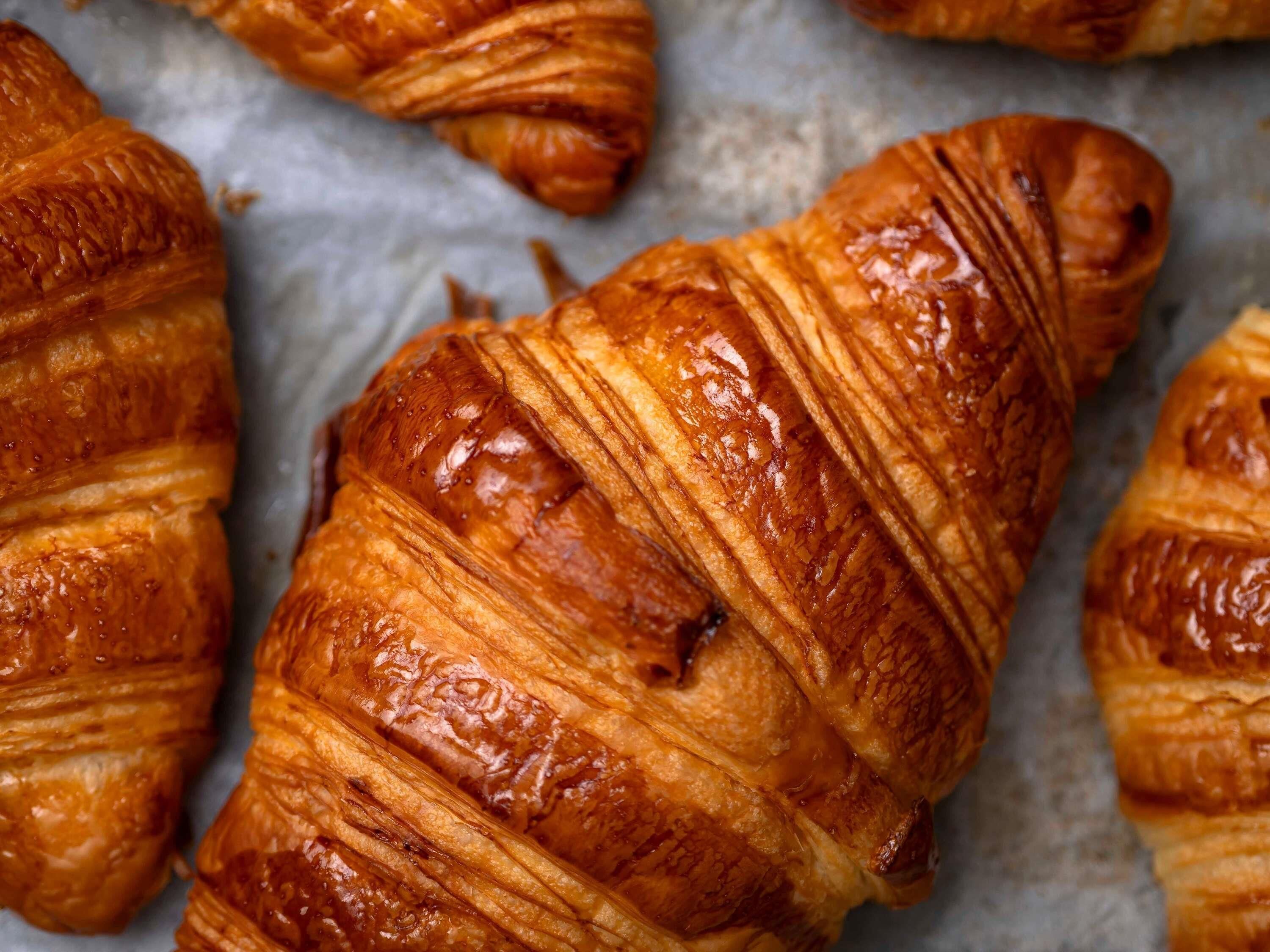 Primer plano de un croissant con una superficie brillante y dorada.