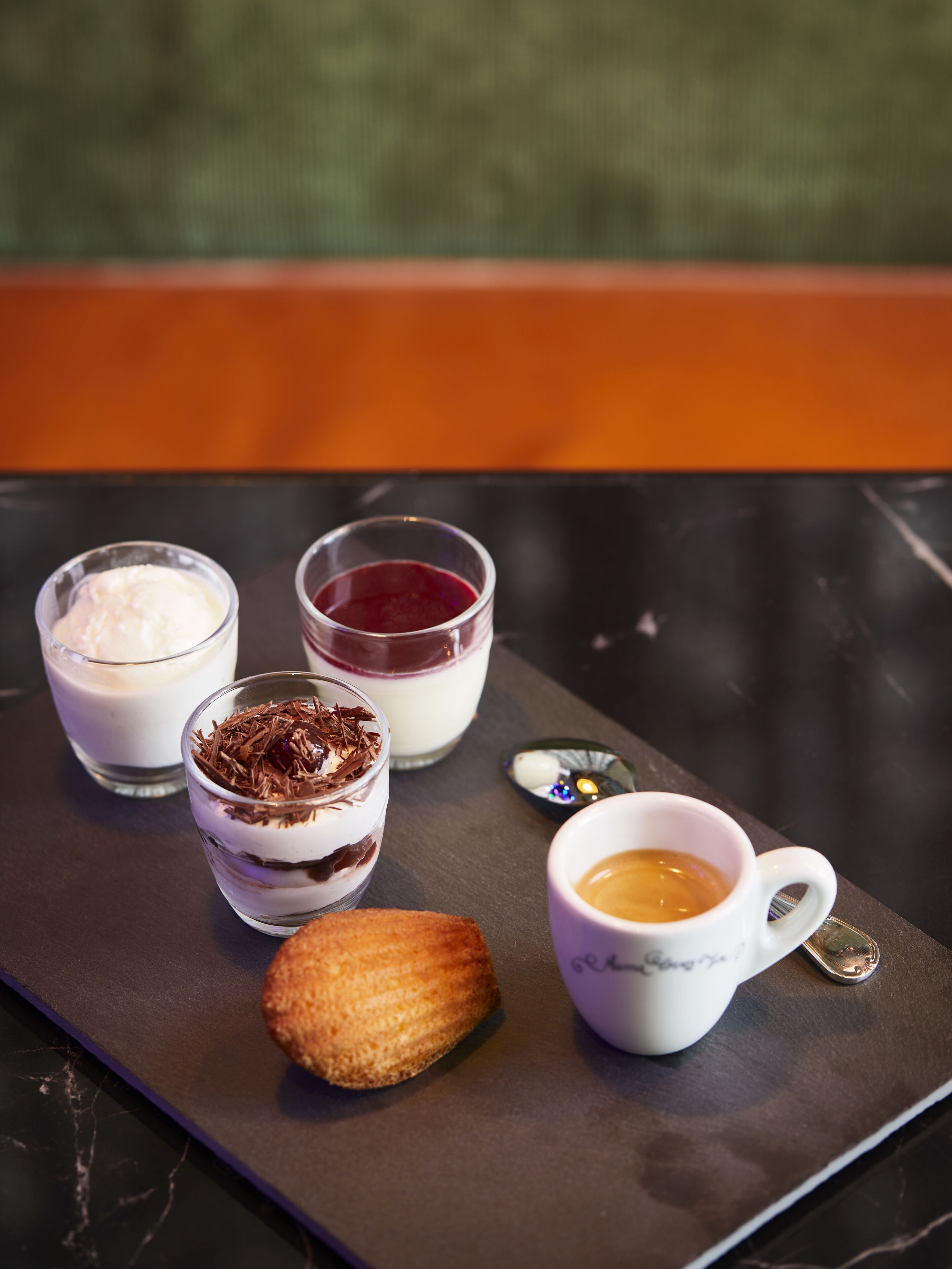 A dessert tray with various desserts and a cup of coffee on a dark table.