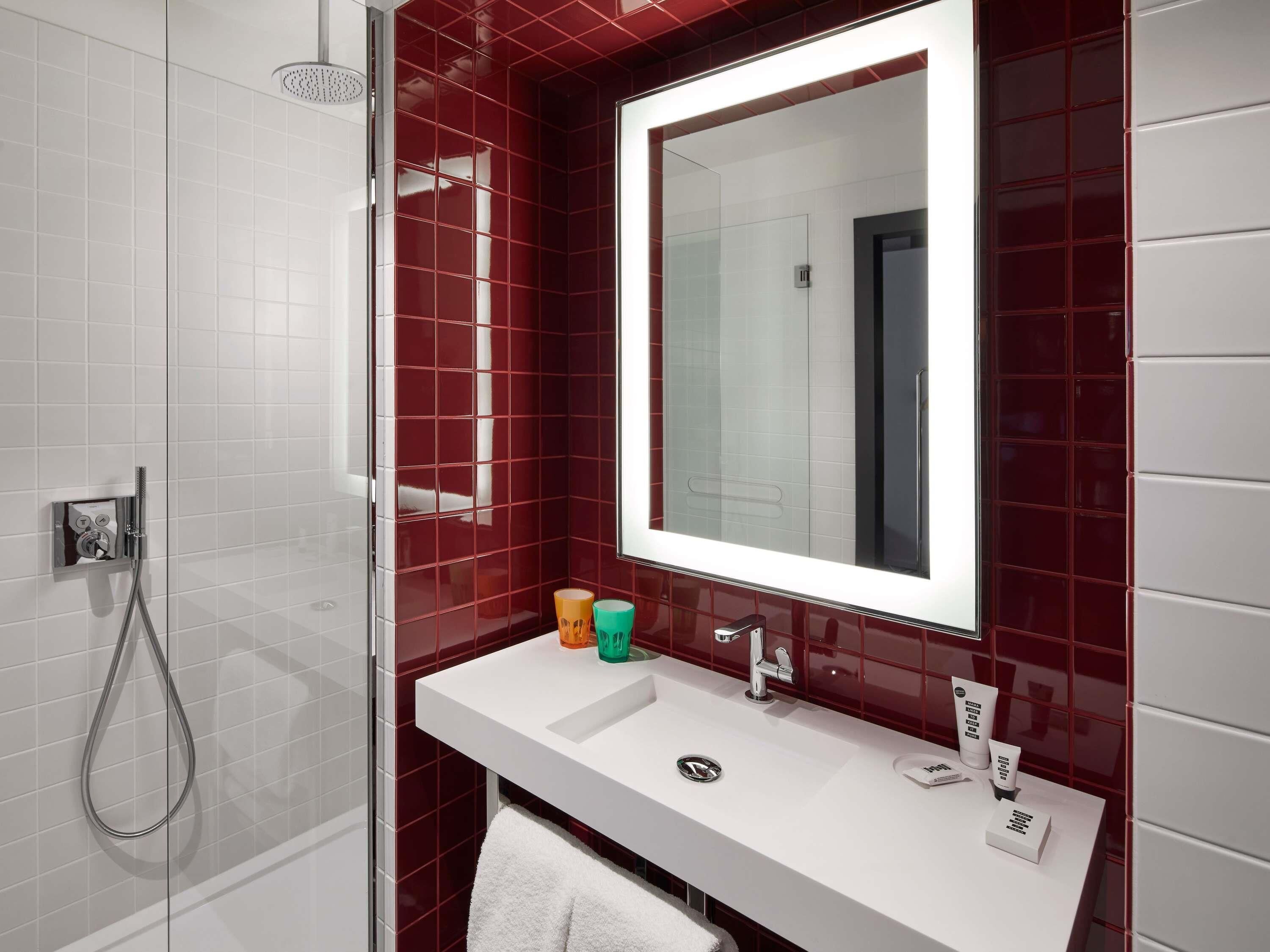 Une salle de bain avec un lavabo blanc, un miroir et une douche.