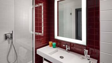 Une salle de bain avec un lavabo blanc, un miroir et une douche.