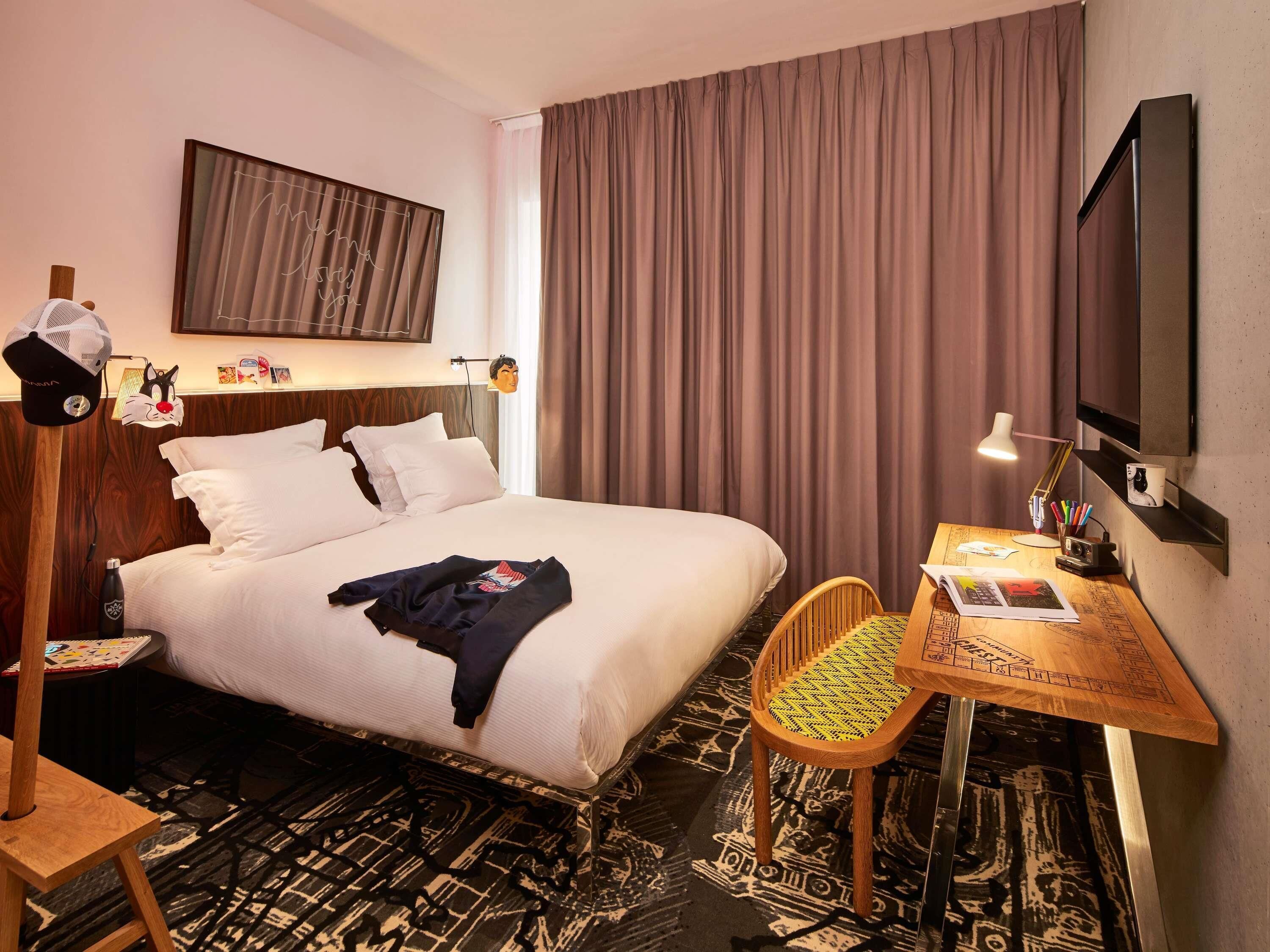 Een hotelkamer met een bed, een bureau, een stoel, een televisie en een kunstwerk aan de muur.