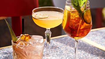 Three glasses of beverages on a table with a red chair in the background.