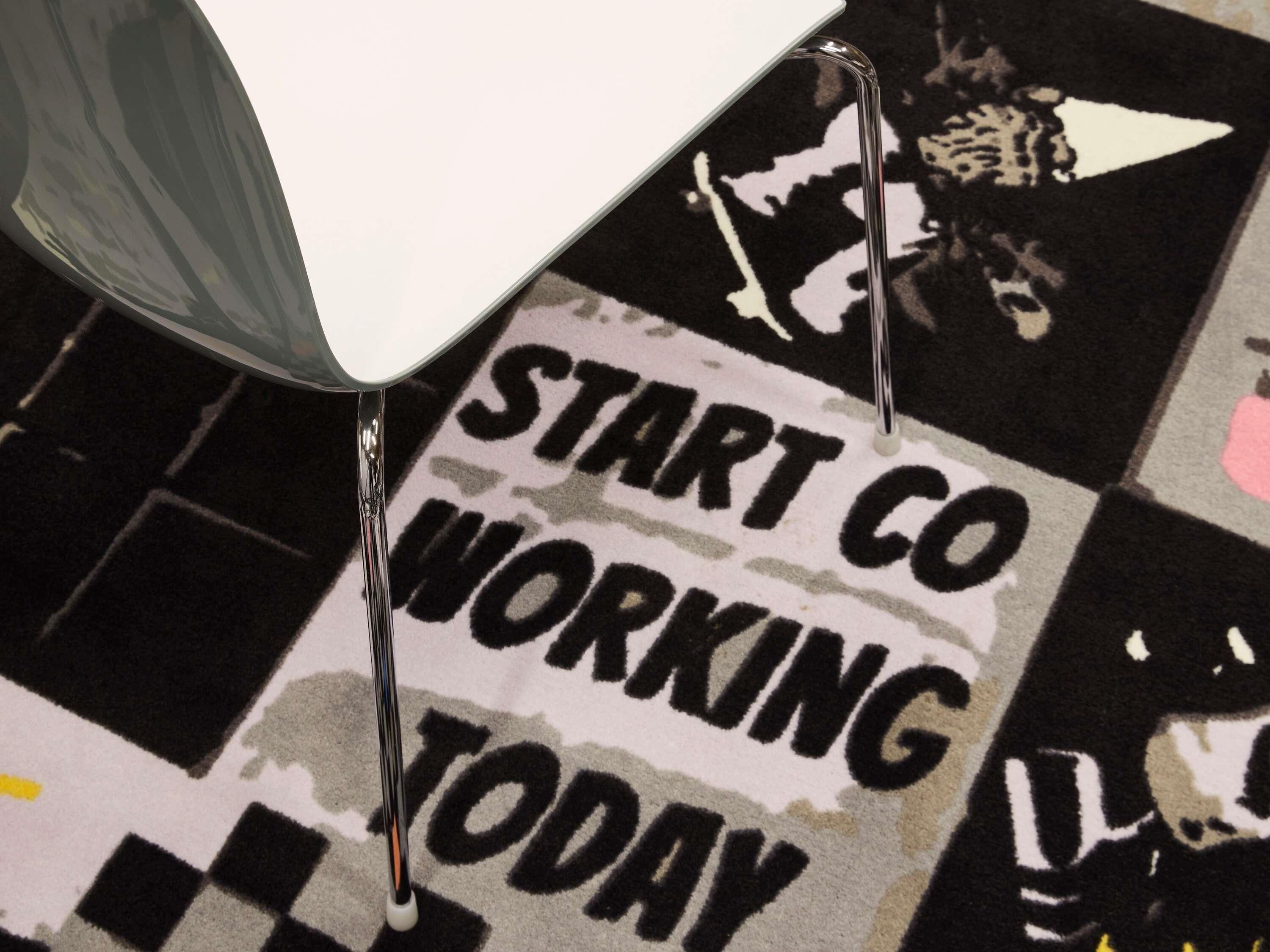 Un tapis sur lequel est inscrit le texte « DÉMARREZ LE CO-WORKING DÈS AUJOURD'HUI » et une chaise.