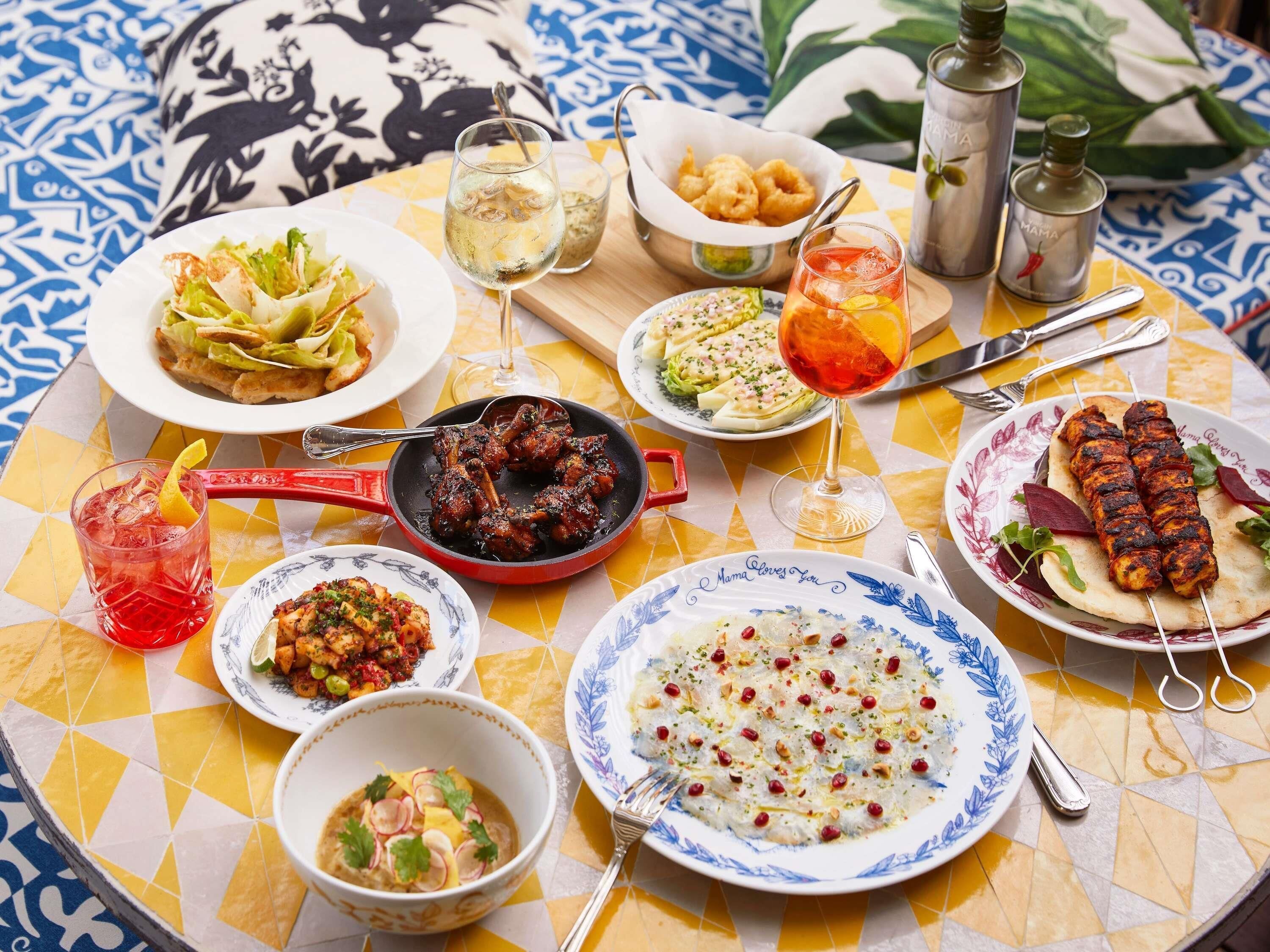 Une table de salle à manger ronde, sur laquelle on trouve différents plats, boissons et ustensiles.