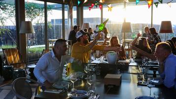 An outdoor dining area with tables set for a meal, surrounded by large windows and a view of the outdoors.