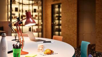 A modern workspace with a laptop, desk lamp, and a croissant on a round table.