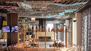 Een bar met een ronde tafel, stoelen en diverse flessen.