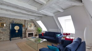 Ein Loft-Wohnzimmer mit Steinwand, einem blauen Sofa, einem Glastisch und einem Kamin.