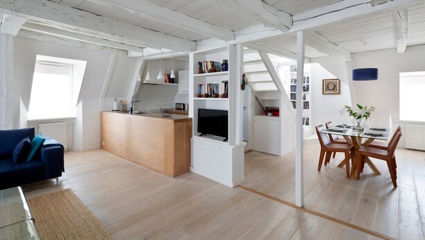 Ein geräumiger Loft mit Küche, Essbereich und Wohnzimmer mit blauem Sofa.