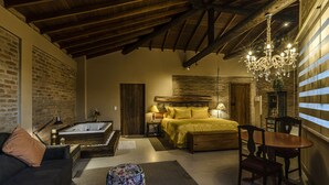 A cozy bedroom with a large bed, a wooden headboard, a chandelier, and a brick wall.