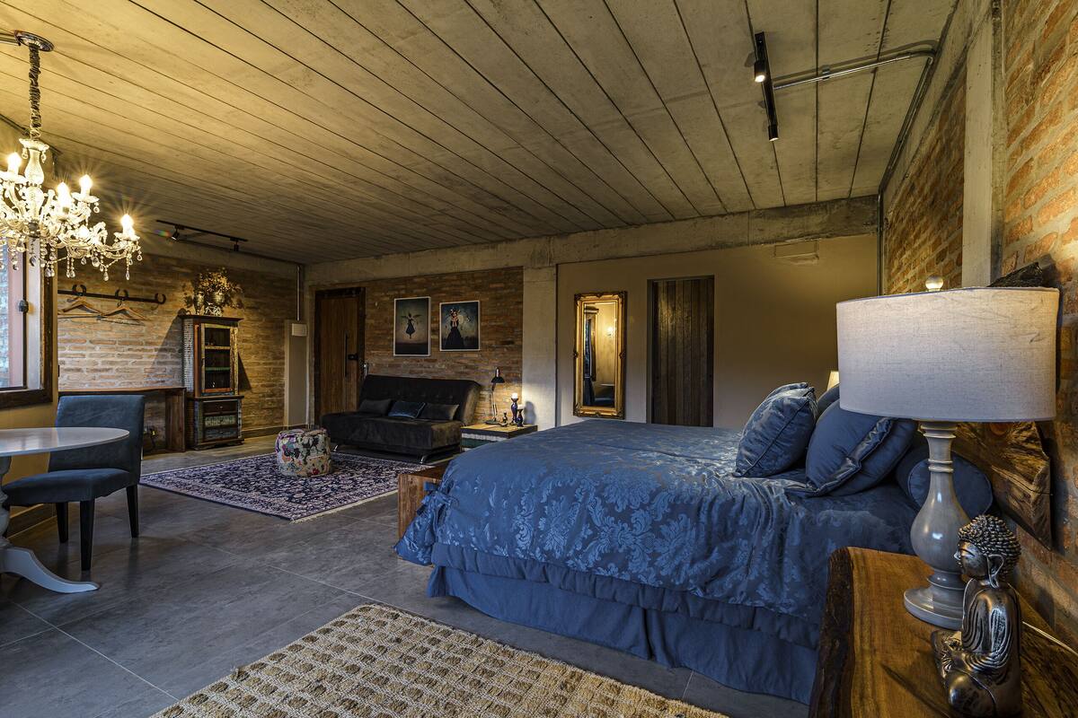 Ein Schlafzimmer mit einem großen Bett, einer Kristallleuchtre, einem Holz-Kopfteil und einem Nachttisch mit Lampe.