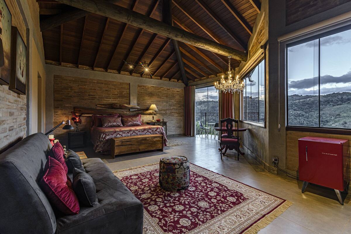 Ein geräumiges Zimmer mit einem großen Bett, einer Couch, einem roten Schrank und Blick auf die Berge.