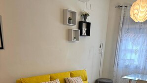 A yellow sofa with two pillows, a white coffee table, and a small side table with a remote control. - K2 2-bedroom apartment (Cáceres)