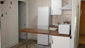 A compact kitchen with a wooden countertop, white cabinetry, and a refrigerator. - K2 2-bedroom apartment (Cáceres)