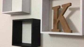 Three framed objects on a wall: two empty frames and one with a large letter 'K'.