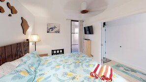 Ein Schlafzimmer mit einem Bett, einem Fernseher, einer Tür und einer Wand mit einem Gemälde.