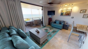 Un salon comprenant un canapé, une table basse, un téléviseur et un balcon avec vue sur la mer.