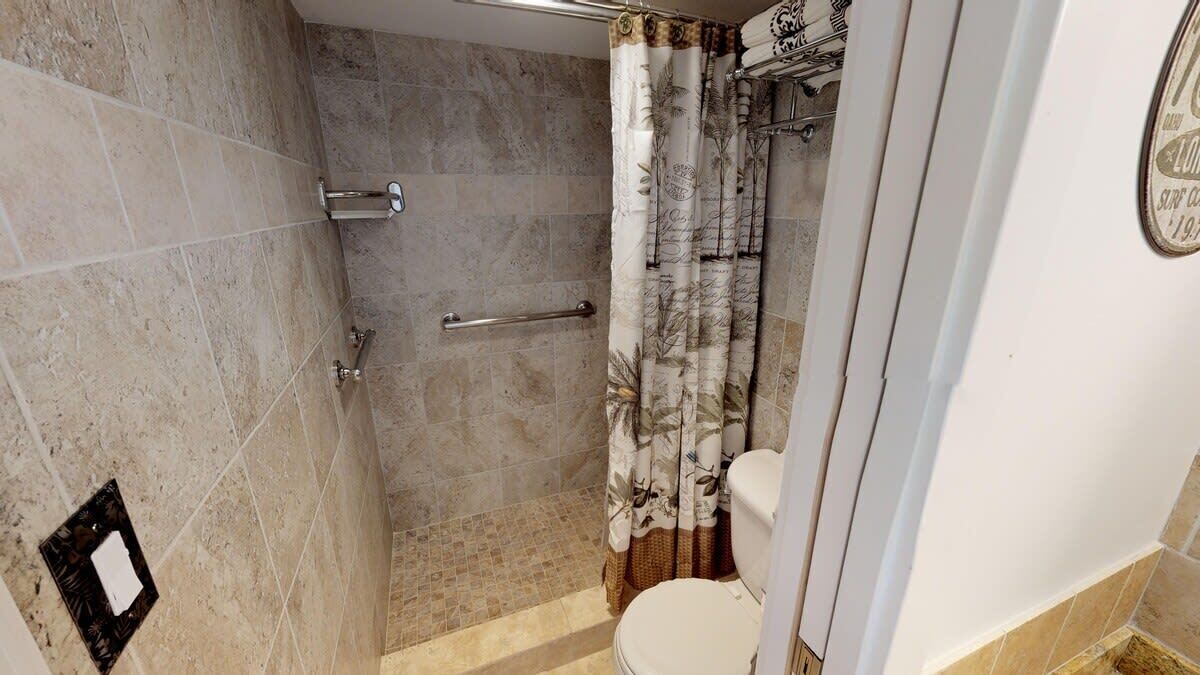 Une salle de bain avec une douche, des toilettes et un porte-serviettes.