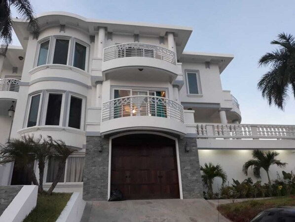A multi-story house with a curved facade, a large garage door, and a balcony with a railing.