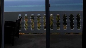 Una stanza con vista sull'oceano, accessibile tramite una porta scorrevole in vetro.