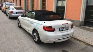 Ein weißer BMW Roadster mit schwarzem Verdeck auf einer Straße geparkt.