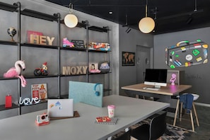 A modern workspace with a desk, laptop, and a computer monitor. There are shelves with various items including books, a globe, and decorative objects. - Moxy Bucharest Old Town (Bucharest)