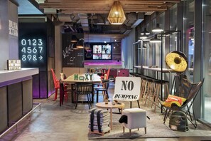 A modern interior with a bar area, seating, and a 'NO DUMPING' sign. - Moxy Bucharest Old Town (Bucharest)