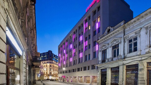 A hotel with a modern facade, multiple floors, and illuminated windows. - Moxy Bucharest Old Town (Bucharest)