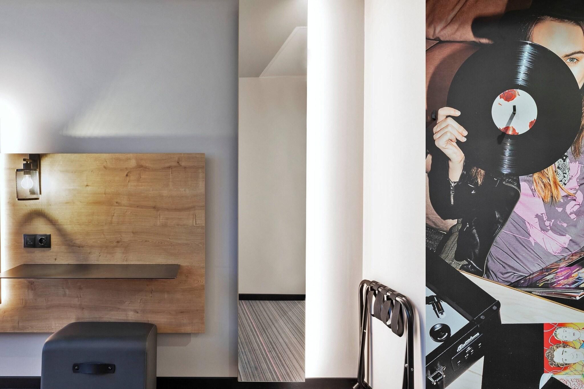 A modern interior with a wooden accent wall, a black speaker, and a large vinyl record artwork.