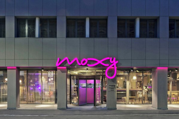 A hotel entrance with a neon sign, glass doors, and a visible interior through the windows. - Moxy Bucharest Old Town (Bucharest)