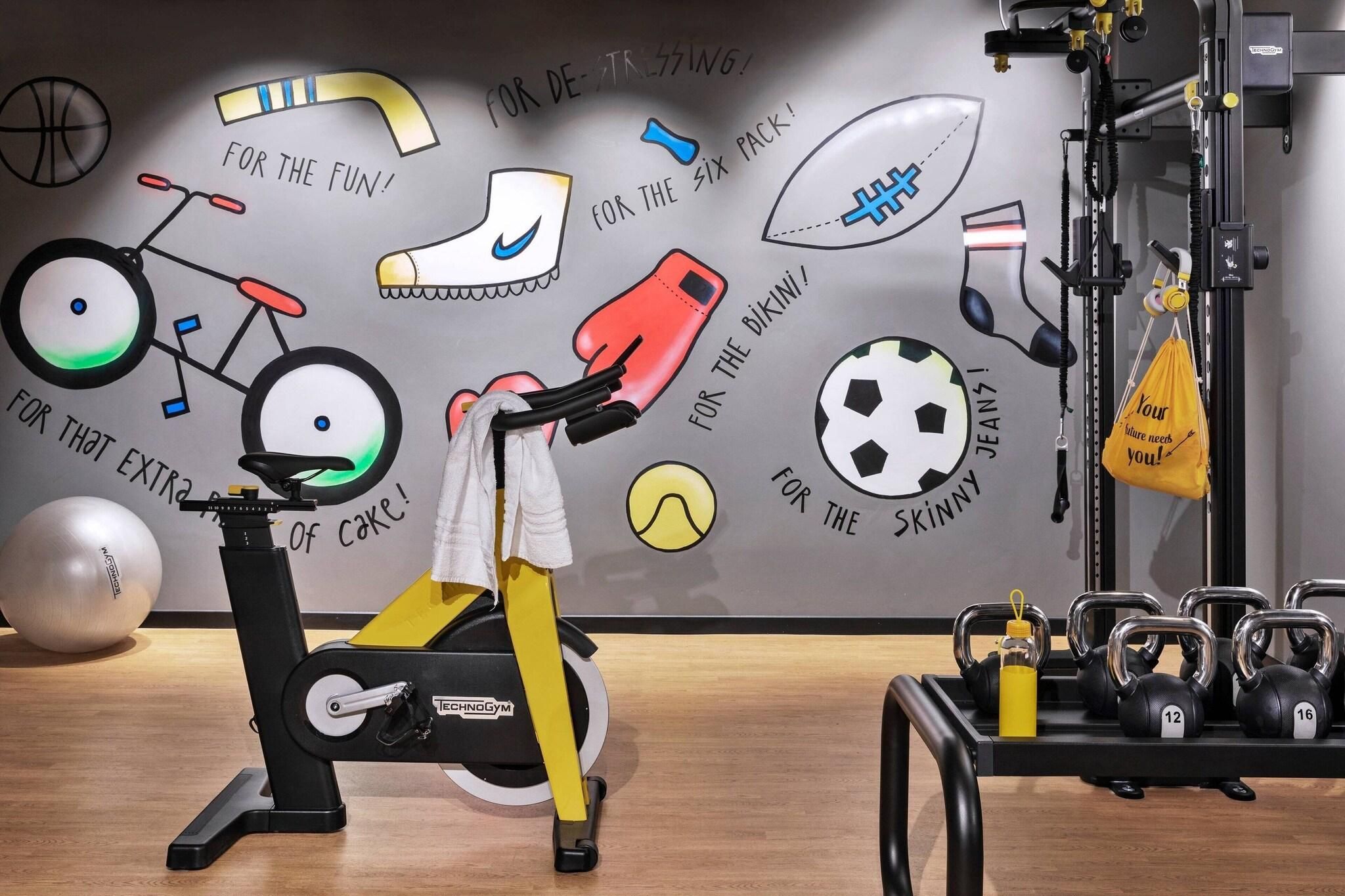 A gym with exercise equipment, motivational wall art, and a kettlebell rack.